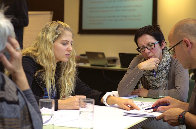 Meeting: Vier Personen beraten an einem Schreibtisch