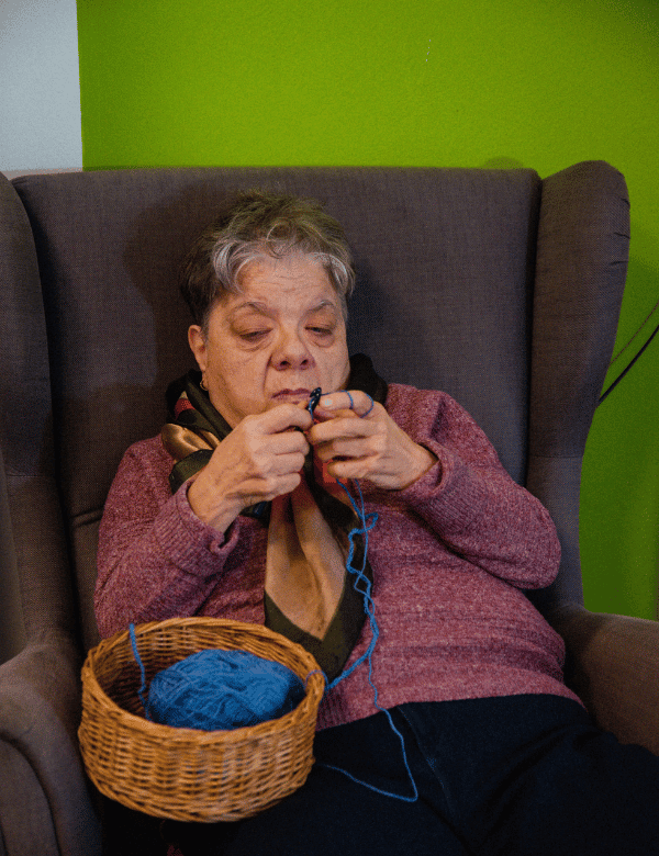 alt Frau im Sessel strickend